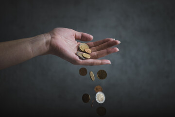 Concept of inflation. Woman hand hold an euro coins. Euro coins falling from woman hand. Declining...