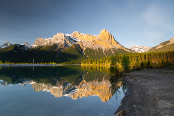 Water reflection of three sisters and ha ling peak mountain range at quarry lake near Canmore Alberta