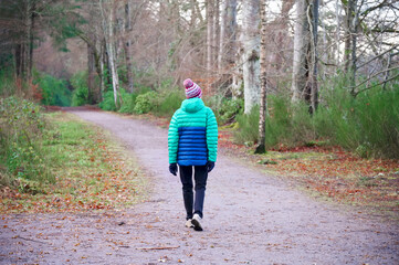 Single elderly woman walking alone in forest for good mental and physical health