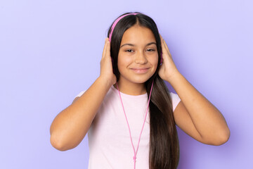 Brunette hispanic girl wearing headphones listening music over purple background