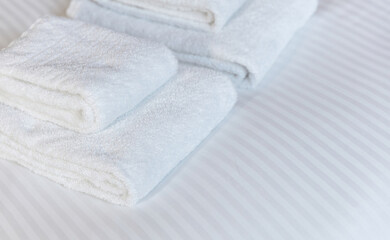Fototapeta na wymiar Fresh white towel on a hotel room bed, close up. Bedroom interior detail, comfort and hospitality