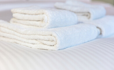 Obraz na płótnie Canvas Fresh white towel on a hotel room bed, close up. Bedroom interior detail, comfort and hospitality
