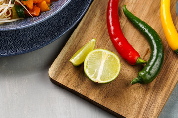 Fresh lime slices and red and green chilli pepper on wooden board