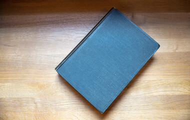 Closed old black book on a table. Blank cover notebook on wooden background, top view. Copy space