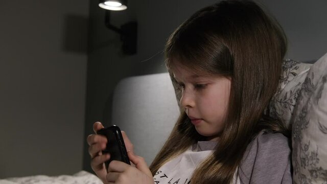 little girl sitting with a smartphone at night, games, online learning