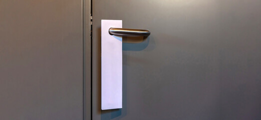 Door knob with blank hanger mock up. Empty white tag for hotel room number hang on a handle.