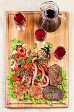 meat and wine on the ceramic tile. three glasses and carafe. view from the top. chicken pork and vegetables on the board