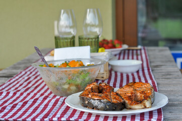 serving table with grilled fish, vegetable salad and vegetables on plates. selective focus macro shot with shallow DOF