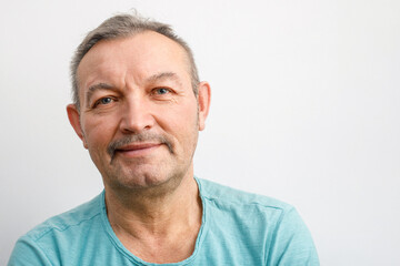 Fototapeta premium Portrait of a friendly elderly man with a mustache. A gray-haired man smiles looking at the camera