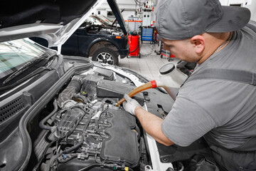 Car mechanic changing oil - model and oil motion blurred.