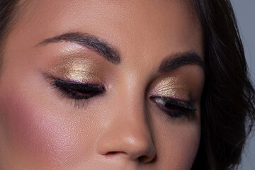 Fototapeta premium Elegance close-up female eye with light pink eyeshadow. Macro shot of part of the face of a beautiful woman. Wellness, cosmetics and makeup. smooth beautiful eyebrows and eyelashes