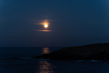 Fototapeta na wymiar Full moon on the coast of Galicia, with lighthouse, natural rock arches, etc!