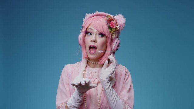 Glamorous funny fancy girl with pink hair and makeup plays like a call center operator comically talking to user or stranger and say hello. Glamour comic phone service support parody conecpt