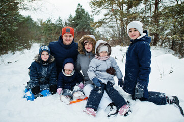 Father and mother with four children in winter nature. Outdoors in snow.