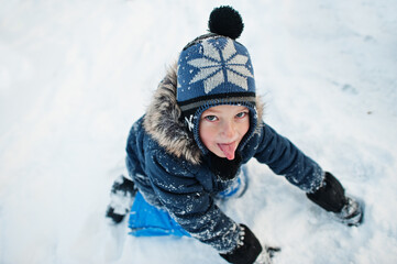 Fototapeta na wymiar Boy show tongue in winter nature. Outdoors in snow.