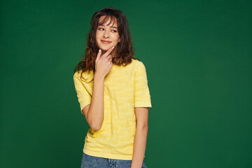 Smiling young pensive girl touching chin, looking aside on empty blank copy space for product, service advertising