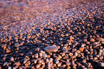 Abstract view of pink rocks and agates with water as a wave comes in, taken in selective focus. Taken at Hunters Point Park in Michigan