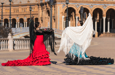Two women in flamenco dress dancing on a square - obrazy, fototapety, plakaty