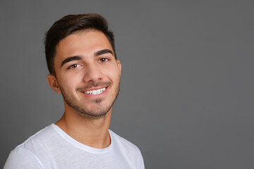 Close-up portrait of handsome smiling guy on gray background. High quality photo, copy space