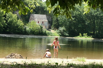 Two kids (twins) playing together in the dordogne river side in front of a fairytale house and some...