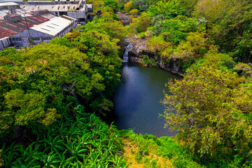 Aerial view of a waterfall hidden in a forest which is located near an old factory in Mauritius