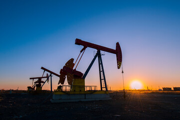 Fototapeta na wymiar Oil pumps are running in the sunset at the oil field. On the Bohai coast of China.