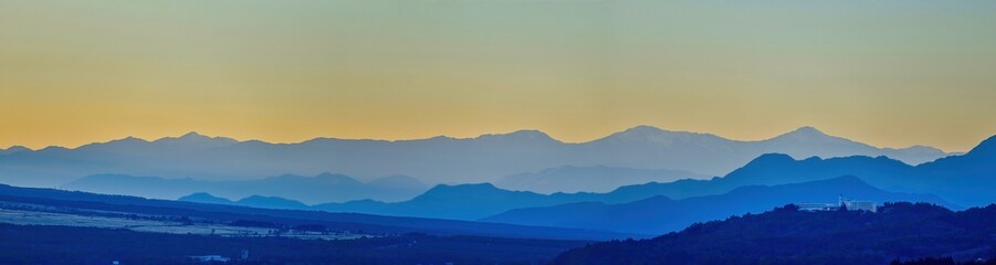 Fototapeta na wymiar 山中湖展望台から見た朝焼けに染まるアルプスの山並みのパノラマ情景＠山梨