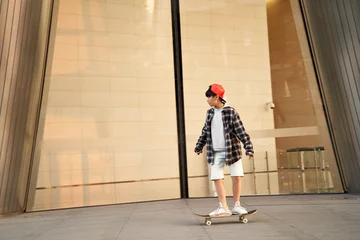 Poster teenage asian boy skateboarding outdoors © imtmphoto