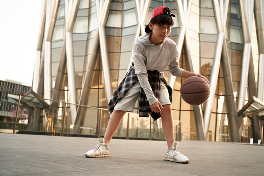 teenage asian boy playing basketball outdoors