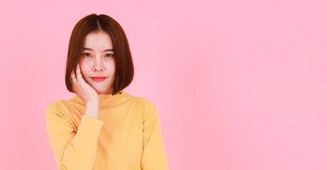 Portrait studio cutout shot of Asian young pretty short hair female model in yellow long sleeve shirt stand smile look at the camera on pink background.