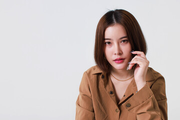 Portrait close up studio cutout shot of Asian stressed depressed worried thoughtful moody short hair female model in long sleeve brown shirt holding hand on forehead have headache on white background