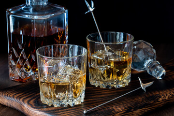 Glasses of whiskey and ice against a dark background.