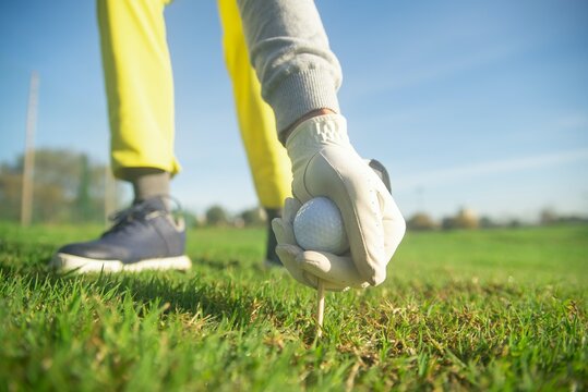 Cropped image of person grabbing the golf ball with pin from the ground