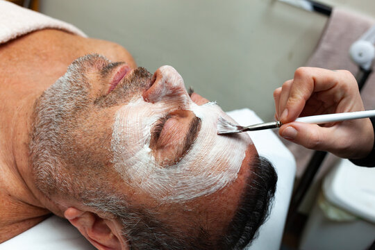 Cropped image of person applying cream on man's face