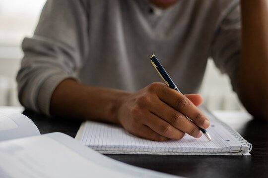 Cropped image of person in gray shirt writing on a notebook