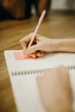 Cropped image of person writing on sticky note on notebook
