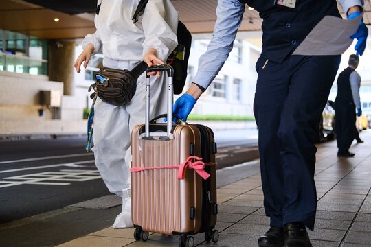 Cropped image of two people with pink luggage bag at the airport