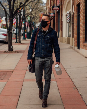 Man with fac mask walking on a sidewalk in downtown Cedar City, UT, US