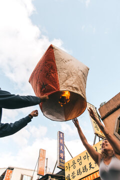 People lighting a sky lantern during daytime