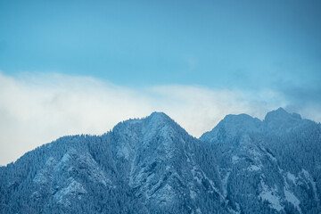 view of the North Vancouver Mountain range on a cold cloudy day covered with thin layer of snow