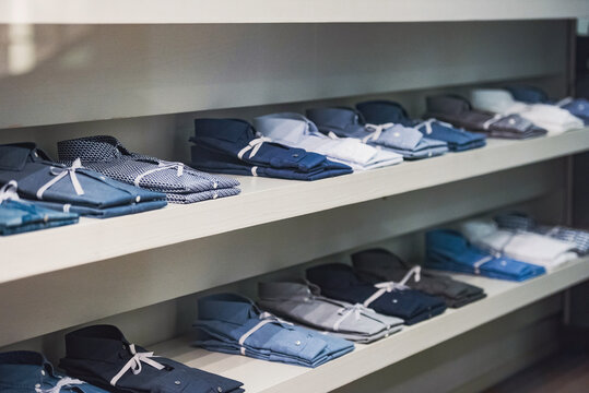 Shelves of folded dress shirts in fashion store