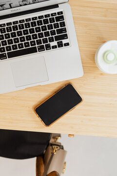 Top view of cellphone near laptop on wooden table