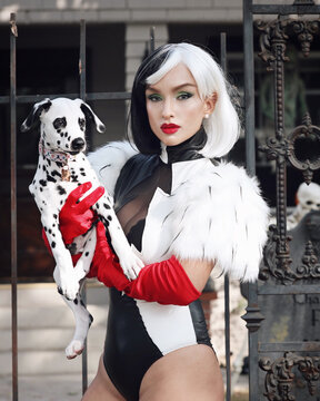 Woman in light and dark polka outfit holding Dalmatian dog