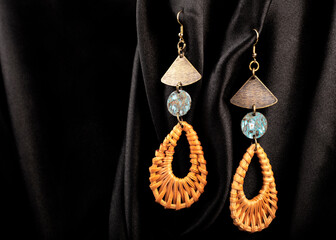 A metal earrings on black silk background.