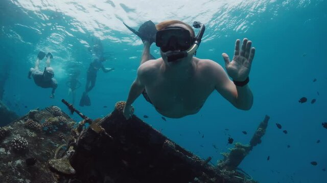 Man swimming and snorkelling on the shipwreck in crystal clear water in Maldives