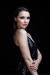 Beautiful young woman in black dress with shining face makeup.