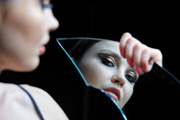 Female with a shard of the mirror. Beautiful young woman portrai