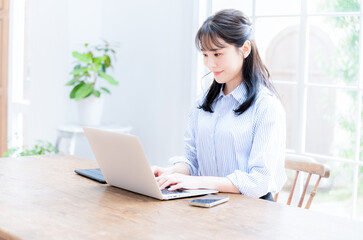 A woman working on a computer in a clean room, from the side. Copying space available.