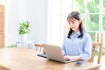 綺麗な部屋でパソコンの仕事をする女性　コピースペース大き目にあり