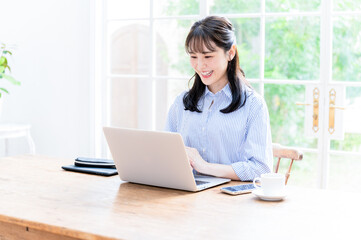メインビジュアルにも使いやすい笑顔でリモートなどパソコンの仕事をする美しい日本人女性